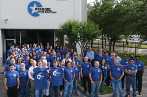 A wide shot of the Stargel team outside of Stargel's building. All are wearing blue Stargel t-shirts.