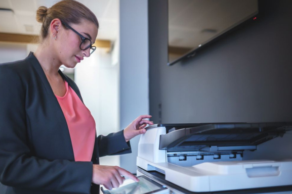 A businesswoman operating an office copier in a modern workspace. Office copiers play a crucial role in streamlining daily business tasks with efficient printing and scanning capabilities.